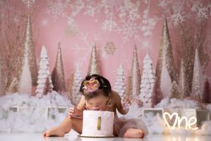 Winter wonderland cake smash setup with pink and white glittery trees and snowflakes.