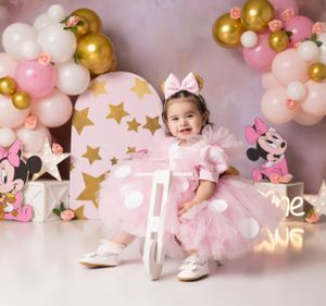 Pink and gold balloon arch setup with star decorations and white picket fence details.