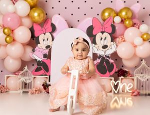 Pink polka dot backdrop with balloon garland and decorative bird cages.