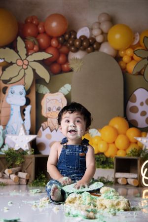 Colorful safari-themed cake smash photography session with balloons, decorations and green frosting.