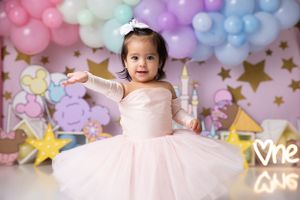 Pink and pastel balloon arch with gold stars creates magical first birthday backdrop.