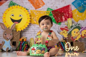 Colorful fiesta themed first birthday photo with papel picado decorations.