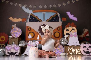 Halloween-themed cake smash with vintage VW bus backdrop and spooky decorations.