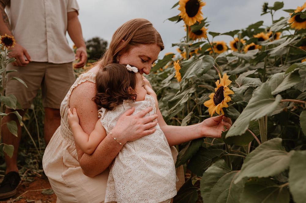 A tender embrace captured among rows of blooming sunflowers on an overcast day.