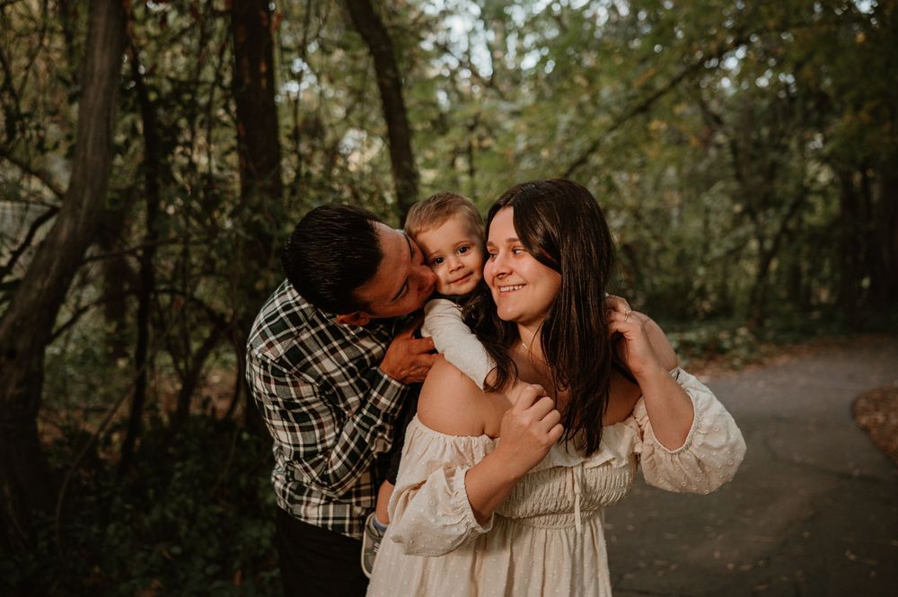Two people share an intimate moment together on a tree-lined path during golden hour.