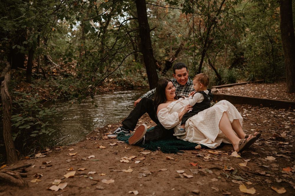 A romantic moment between a couple sitting together by a stream in an autumn forest.