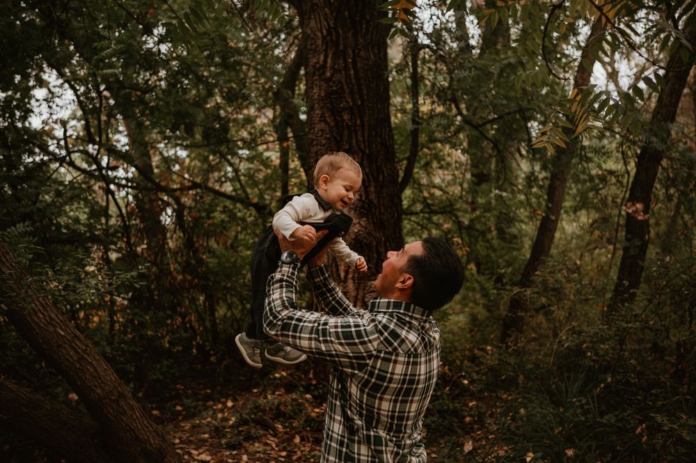 A tender moment between parent and child playing together in a wooded forest setting.