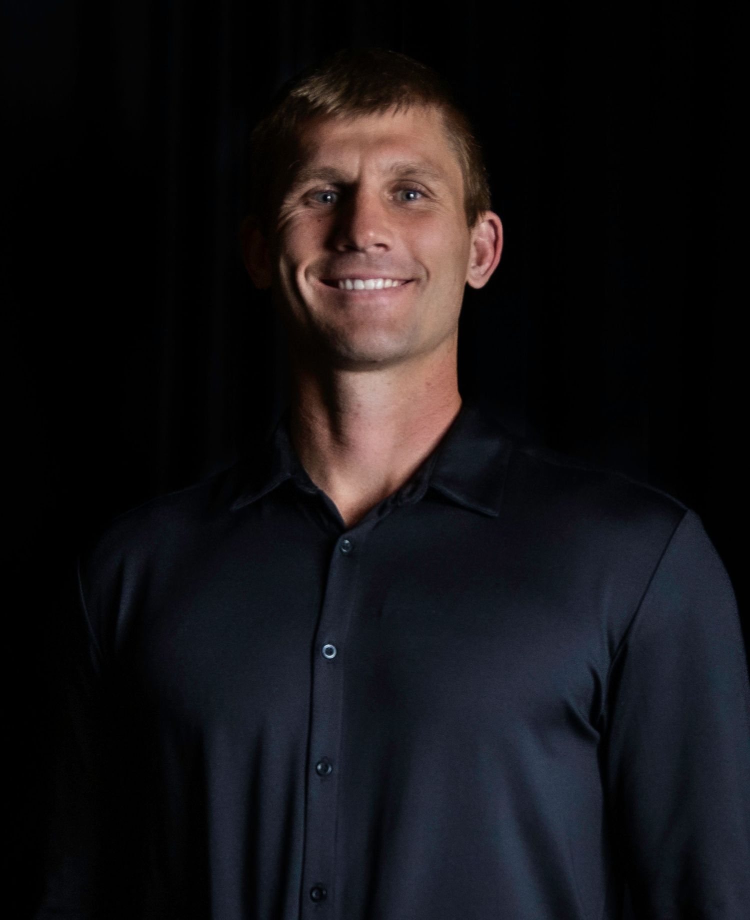 Dramatic black and white studio portrait series showing a dark navy shirt against black background. Professional headshot, Chandler, AZ