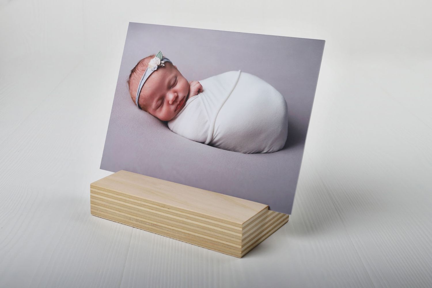 Un portrait professionnel de bébé posé sur un support en bois contre un fond blanc.