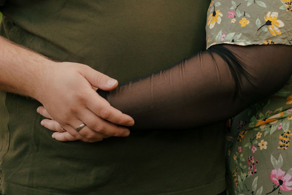 Two hands tenderly clasped together against a dark background.