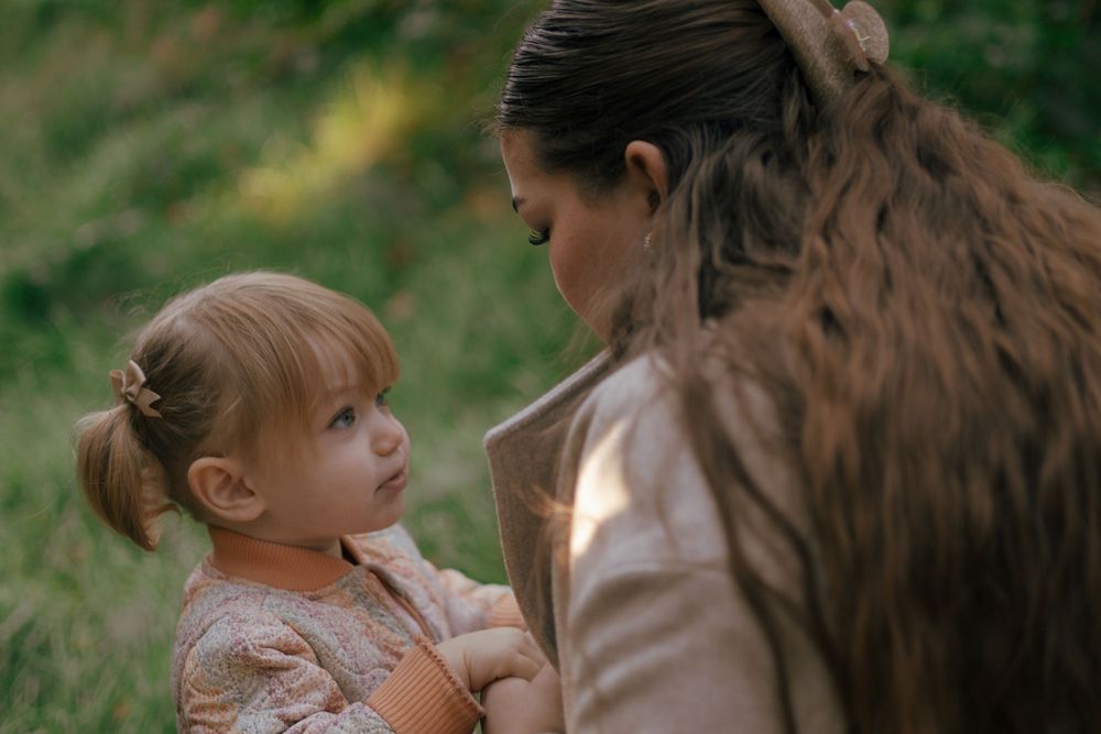 A tender moment between adult and child outdoors with soft lighting and natural background.