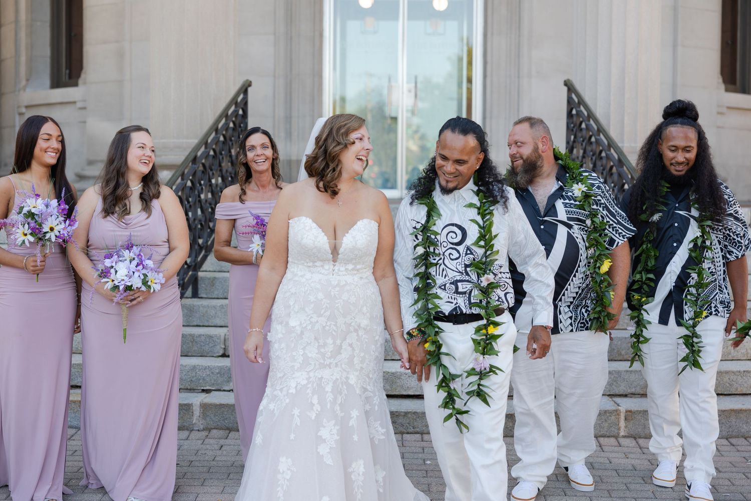 Bride and groom walking with bridal party laughing and enjoying a candid moment together.