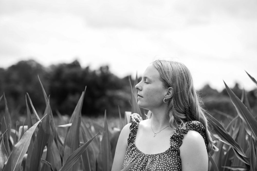 Black and white artistic portrait showing a contemplative moment in a field of tall grass.