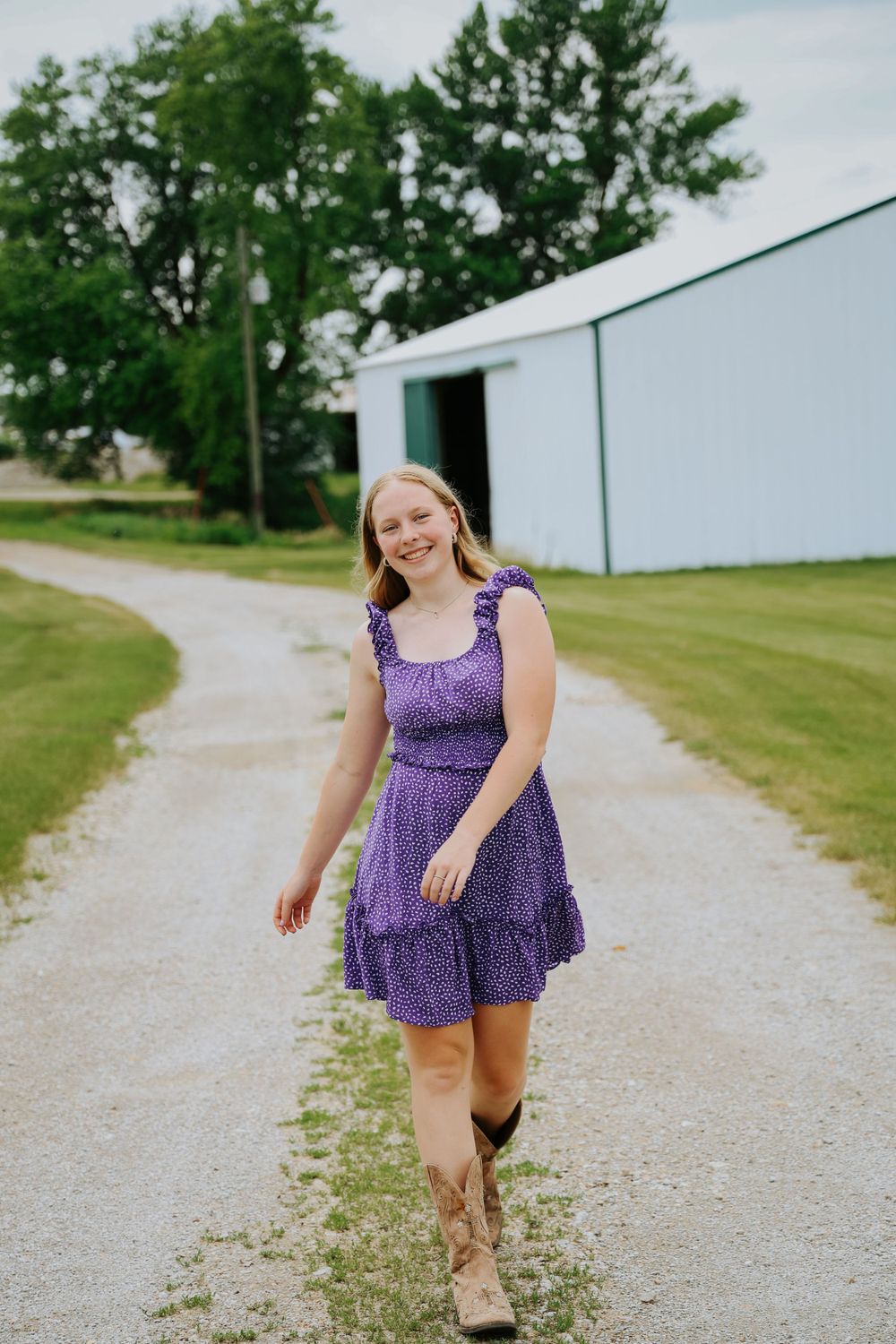 Carefree summer moment walking barefoot down a gravel path in a purple dress.