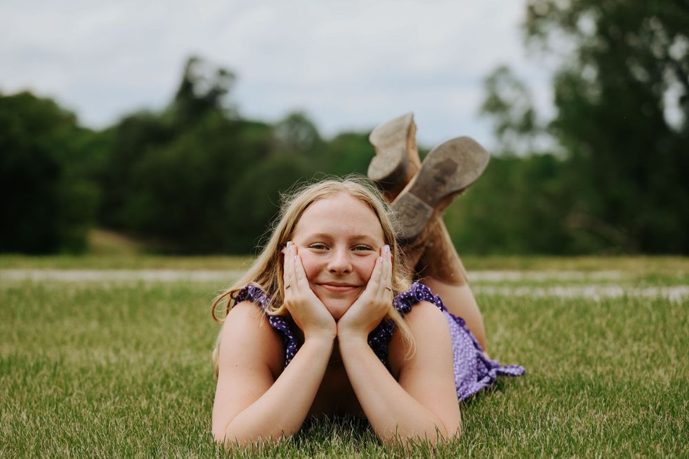 Relaxed outdoor portrait lying in green grass wearing brown boots.