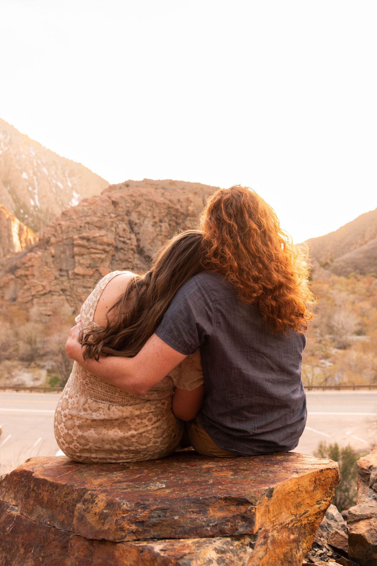 Person in black shirt rests on rocky outcrop during golden desert sunset.