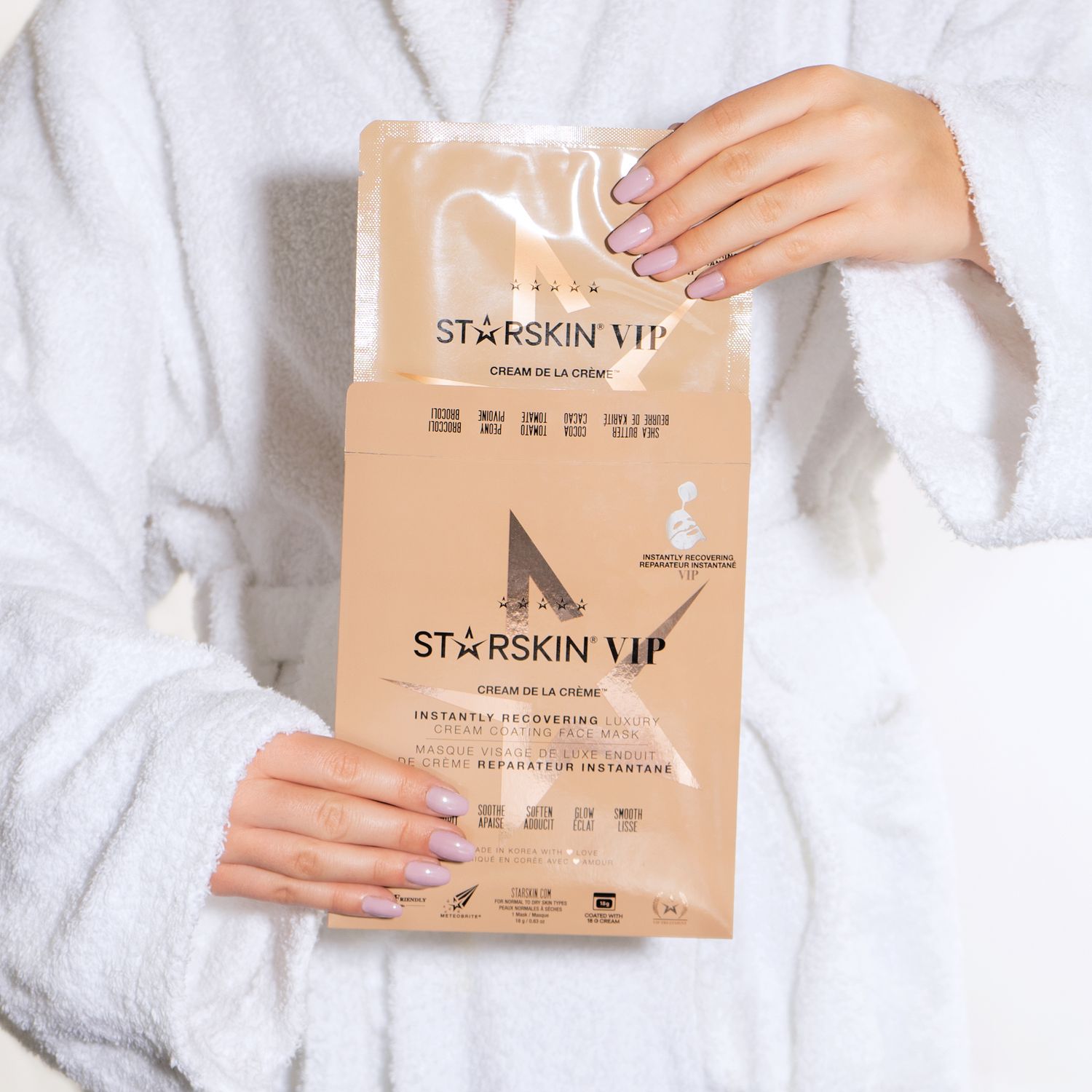 Een lichte productfoto van een beautyproduct, vrouw houdt verpakking voor, ze draagt een witte badjas en haalt het product uit verpakking