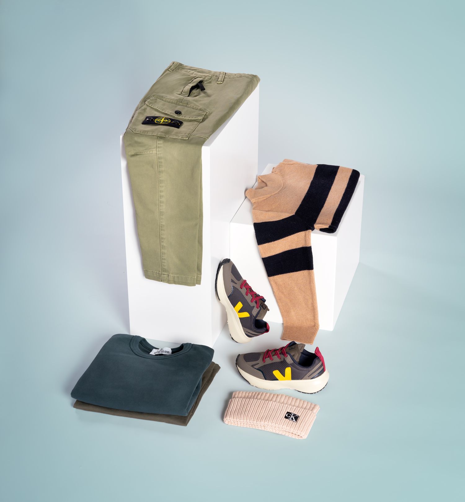 Een display met stijlvolle kinderitems, gepresenteerd op witte blokken tegen een lichtblauwe achtergrond.