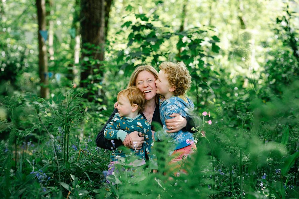 A loving family embrace captured in a lush green forest setting.