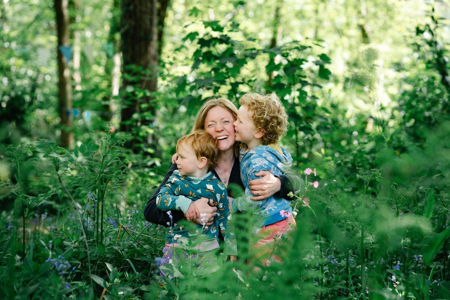 A loving family embrace captured in a lush green forest setting.