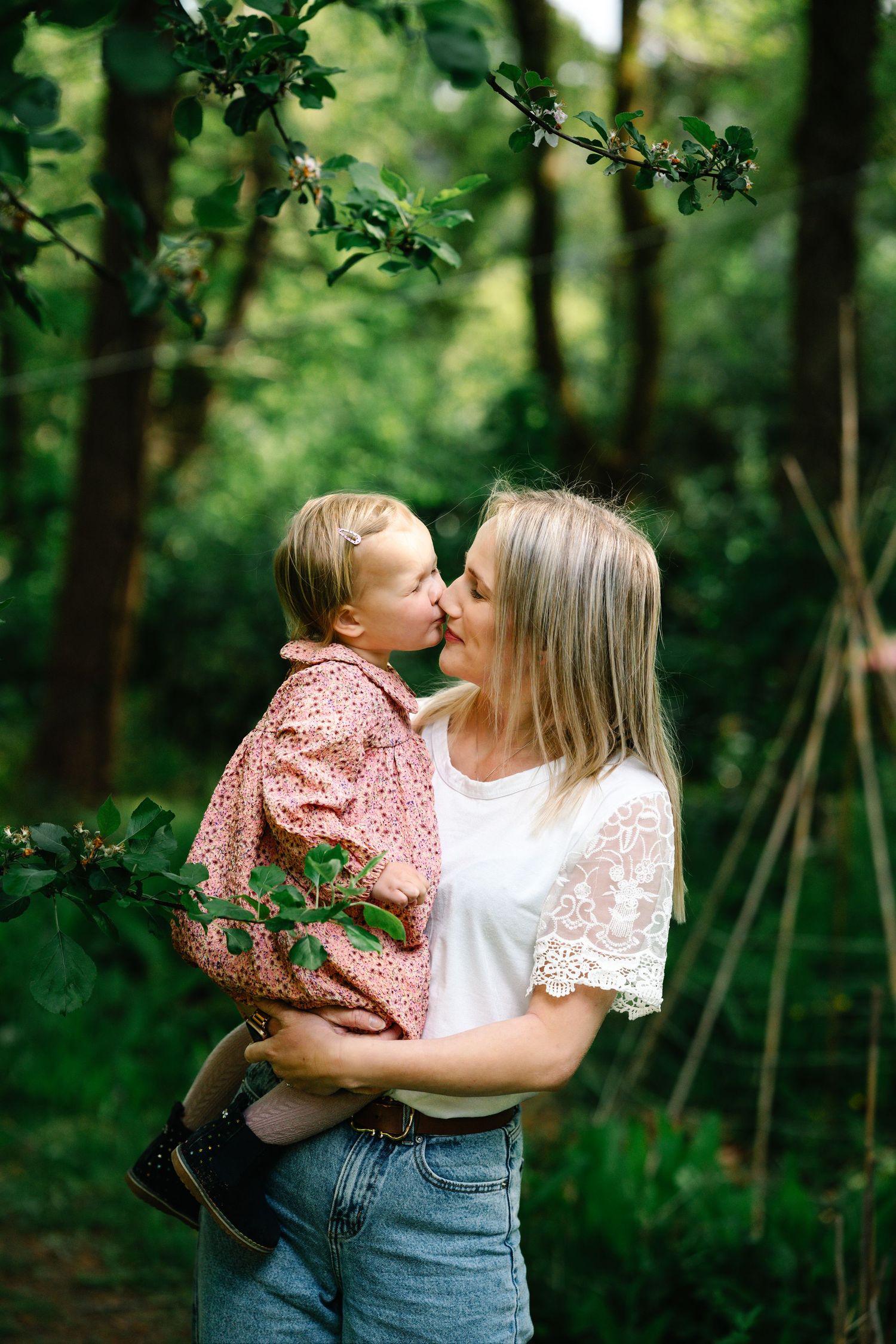 Mother and child sharing tender moments in a lush green forest setting.