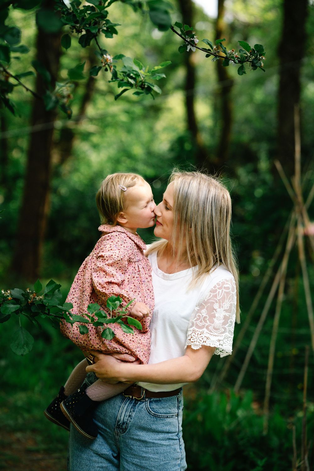 Mother and child sharing tender moments in a lush green forest setting.