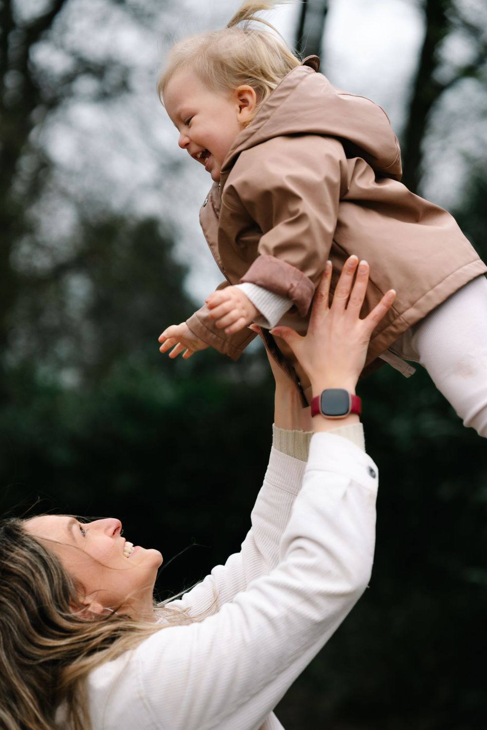A playful moment captured as a parent lifts and plays with their laughing baby outdoors.