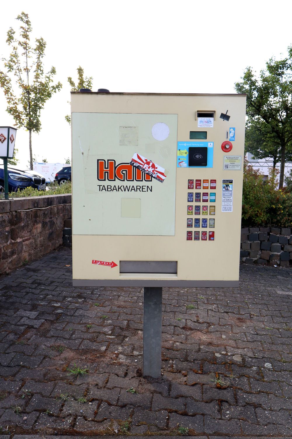 White vending machine for parking tickets mounted on a brick wall.