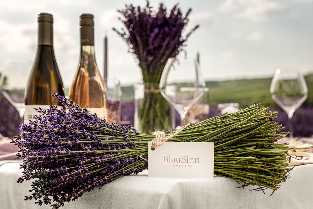 Fresh lavender bundles and wine bottles arranged on white tablecloth with place cards.