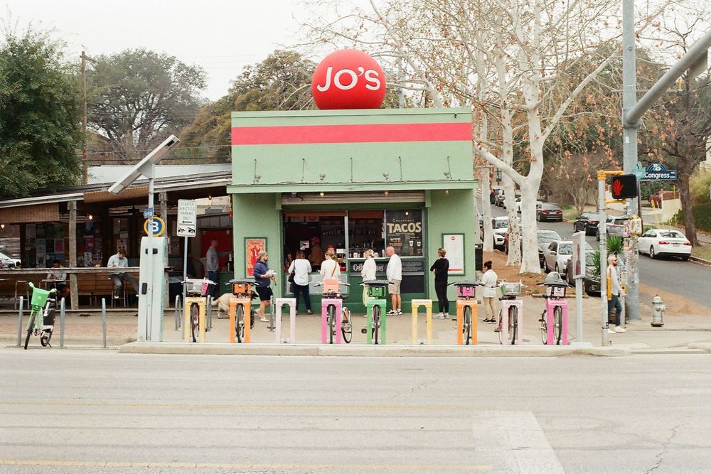 Jo's Coffee shop exterior in Austin, TX with colorful bikes parked outside on a sunny day.