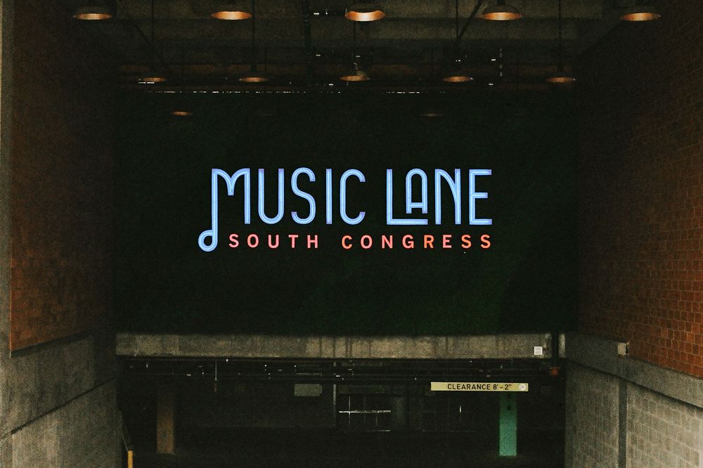 Illuminated Music Lane South Congress sign displayed on a dark wall in Austin, Texas.