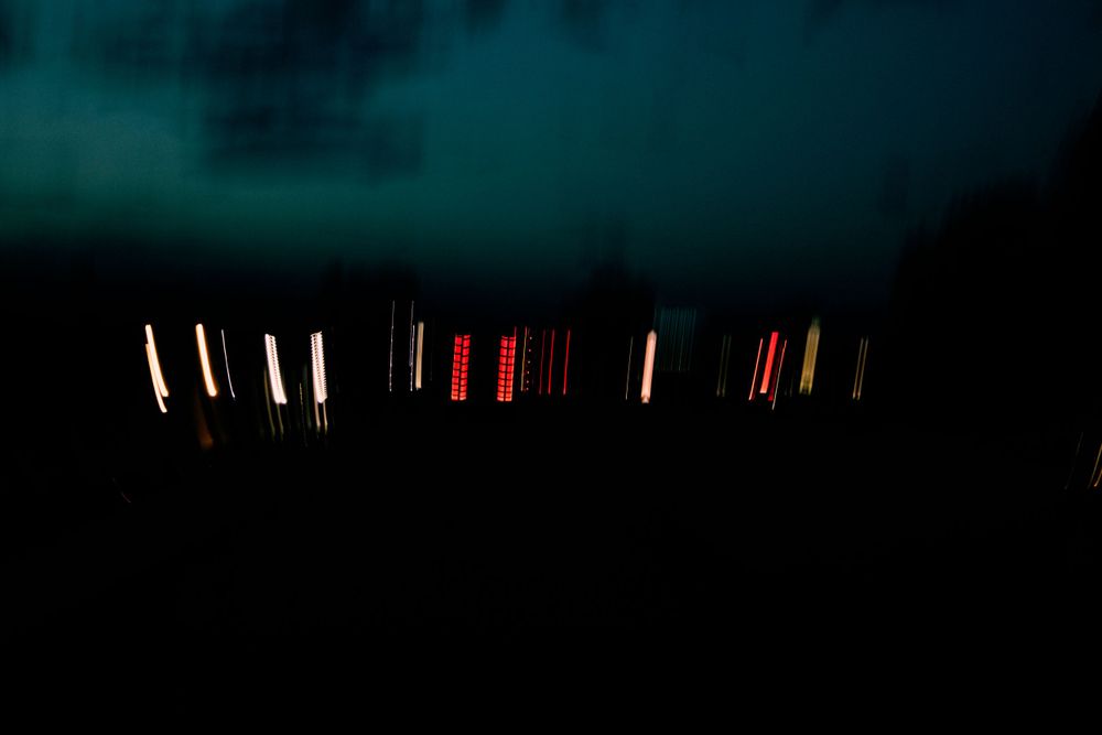 Blurry red and white lights illuminate a dark nighttime scene in an abstract way.