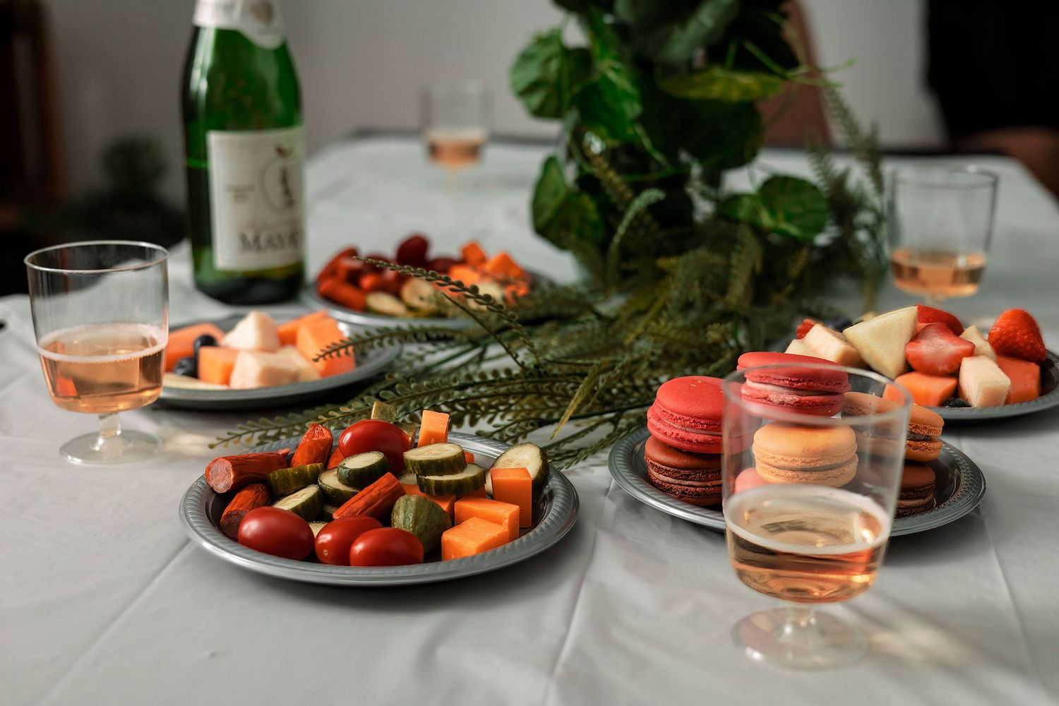 Fresh fruit and appetizers served on white plates with wine glasses on an elegantly set table.