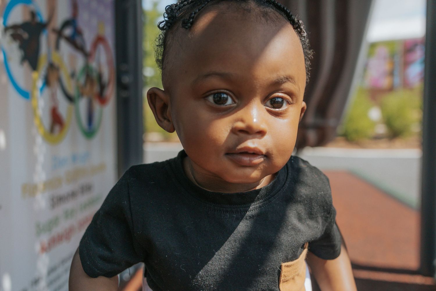 A toddler in a black t-shirt looks directly at the camera with an expressive face.