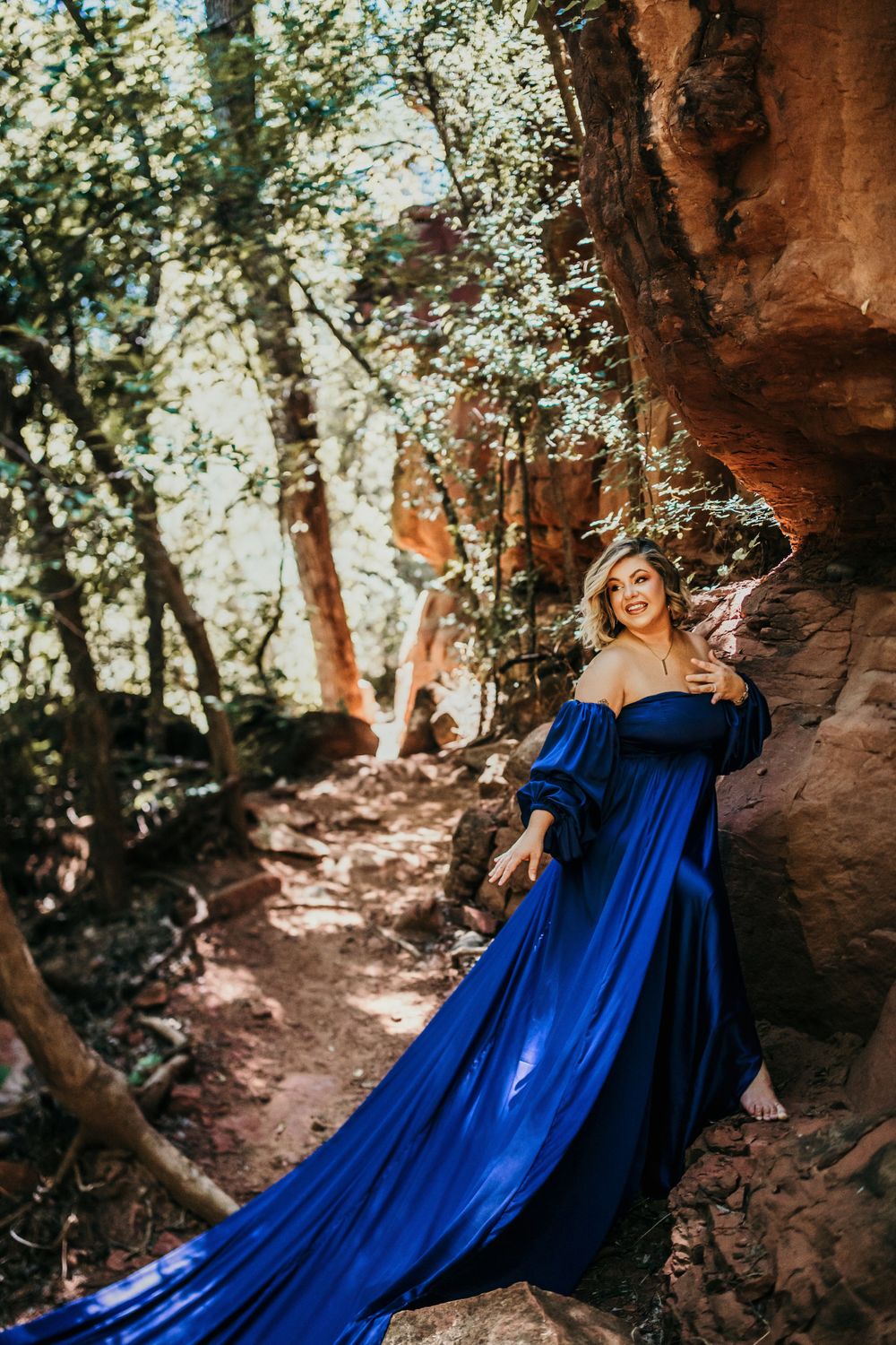 Stunning blue gown creates dramatic silhouette against red rock cave formations.