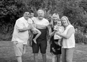 Black and white family photo of six people including two babies in a garden.