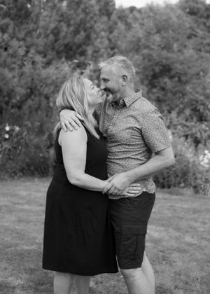 Black and white photo of a smiling couple embracing outdoors in a garden.