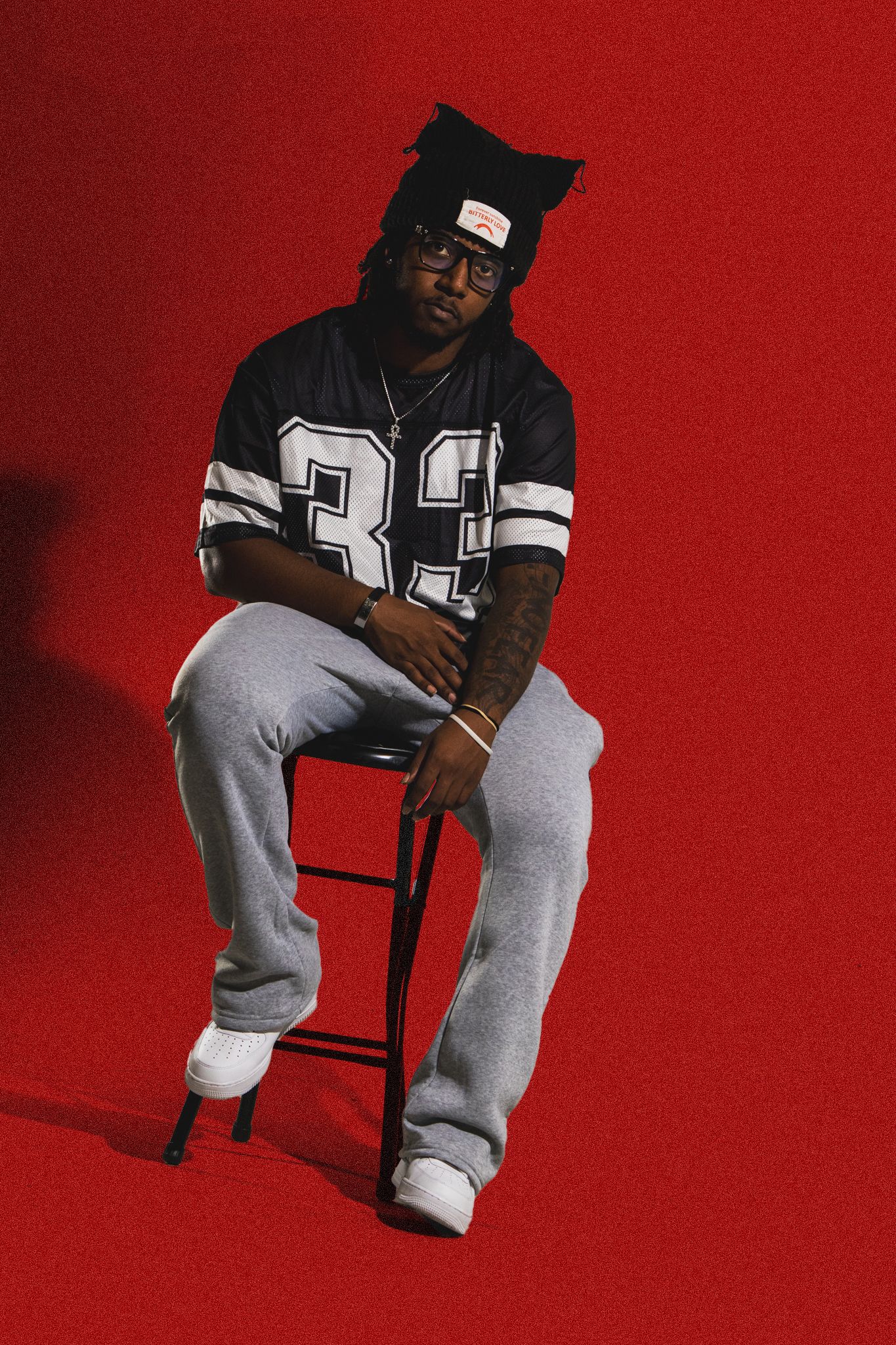 Athletic style portrait featuring North Face beanie and jersey against red backdrop.