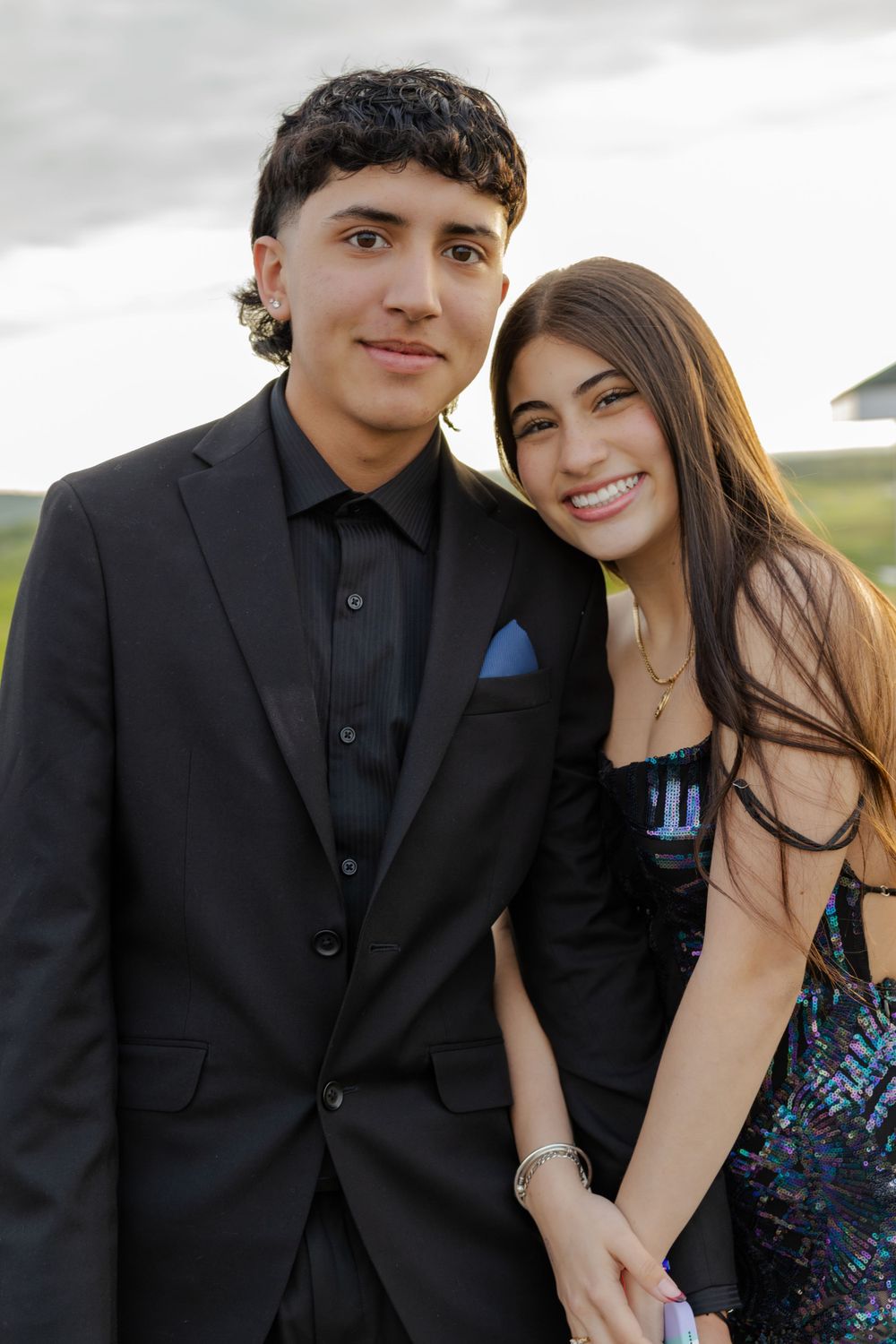 Young couple in formal attire share intimate moment during outdoor photo session.
