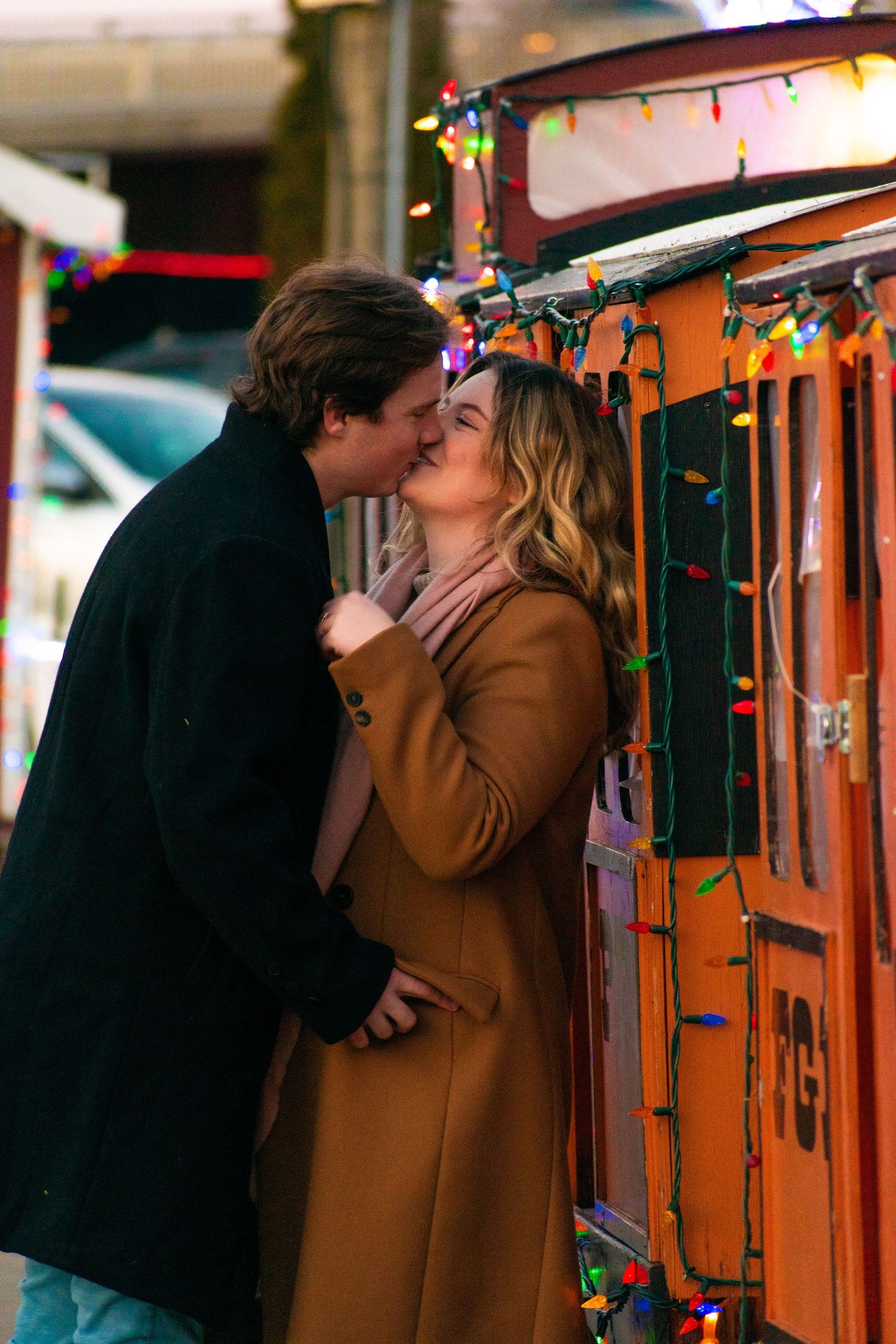 A romantic scene beside an orange wall decorated with colorful holiday lights.