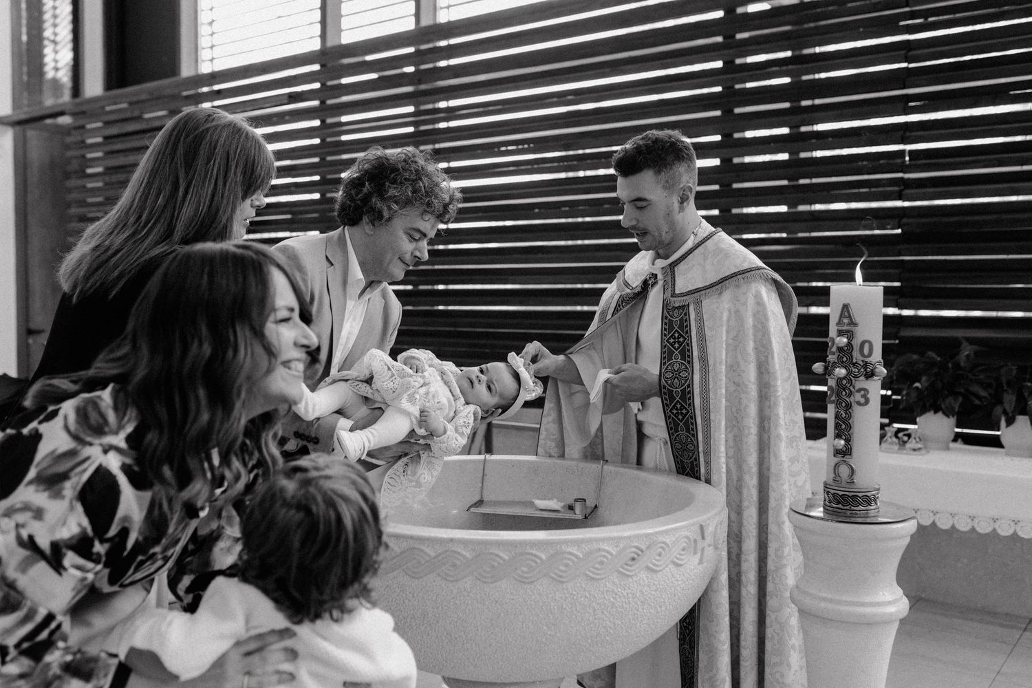 A black and white photo capturing a baptism ceremony at a church font.