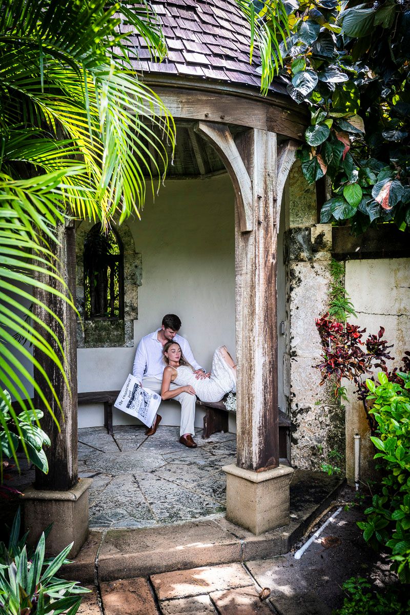 Couple relaxing in a tropical garden gazebo with lush palm fronds and climbing vines.