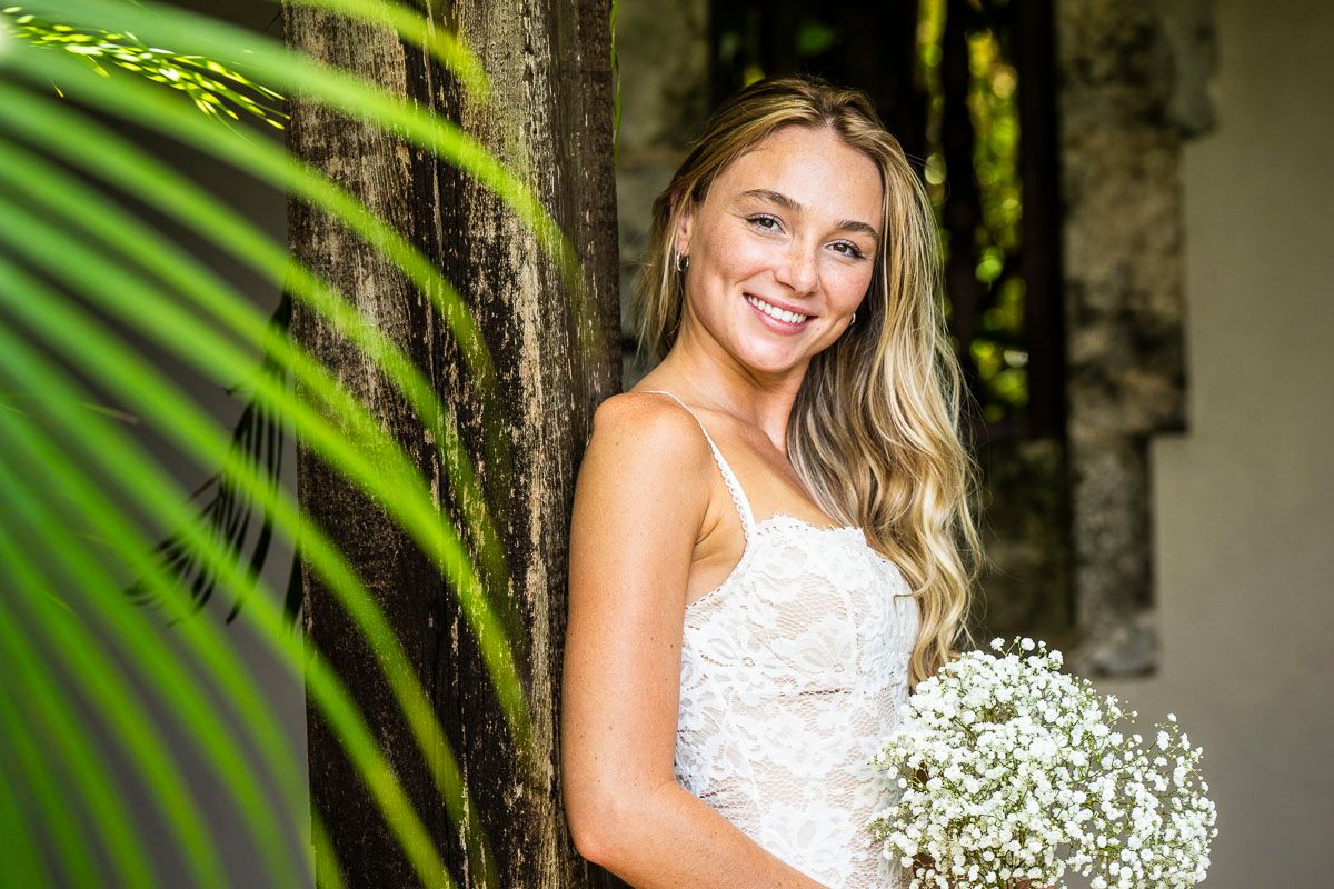 Elegant white dress and bouquet amid tropical garden setting.