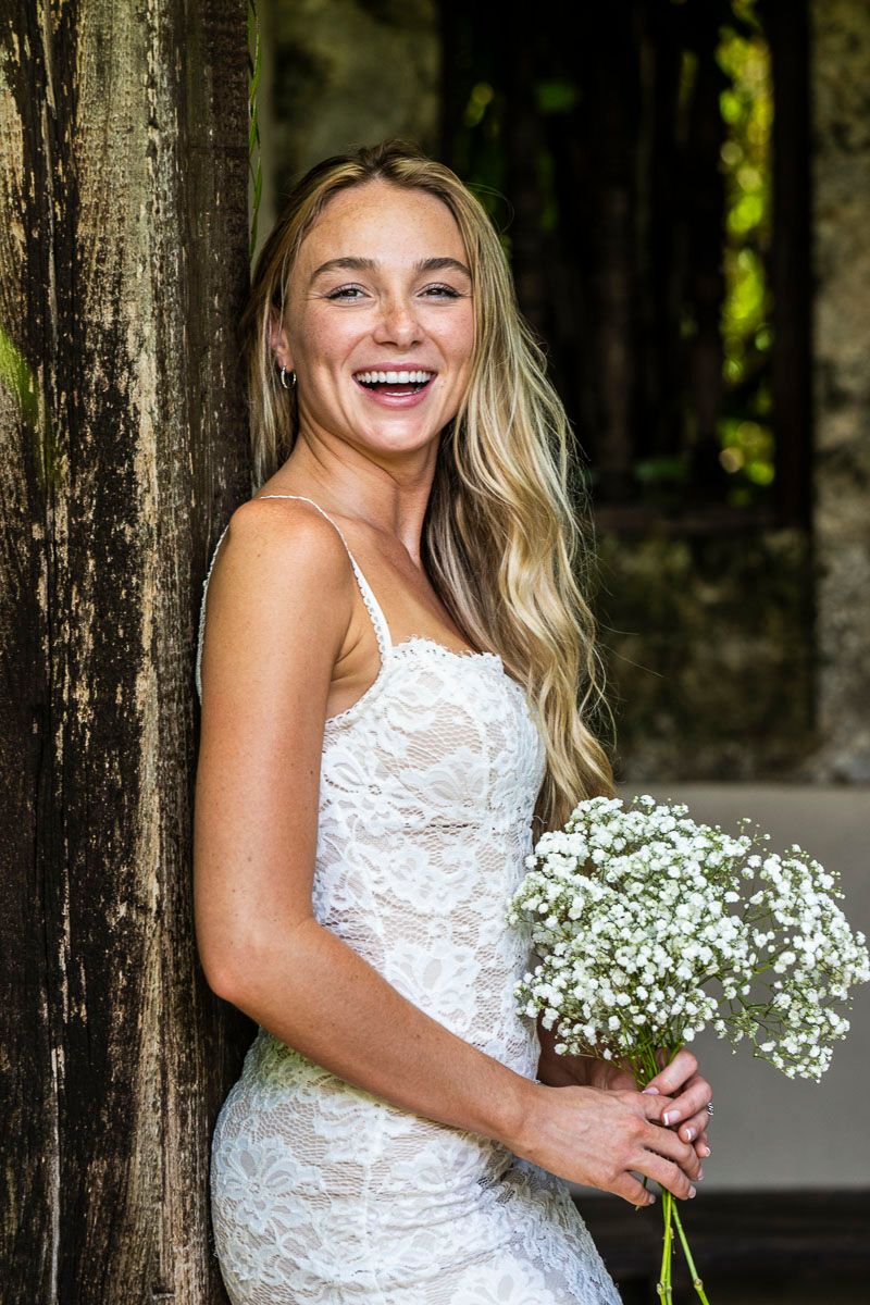 Joyful moment captured with white bouquet and lace dress against rustic backdrop.