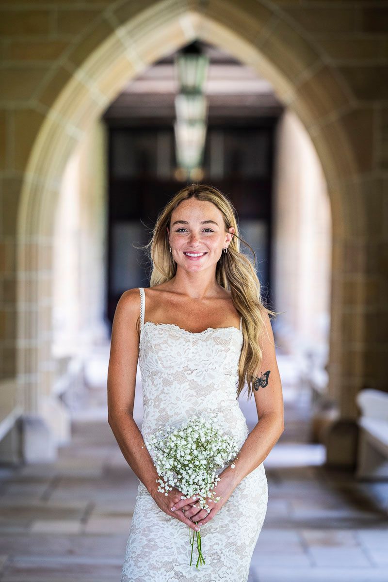 Elegant white dress and baby's breath bouquet in stone archway setting.