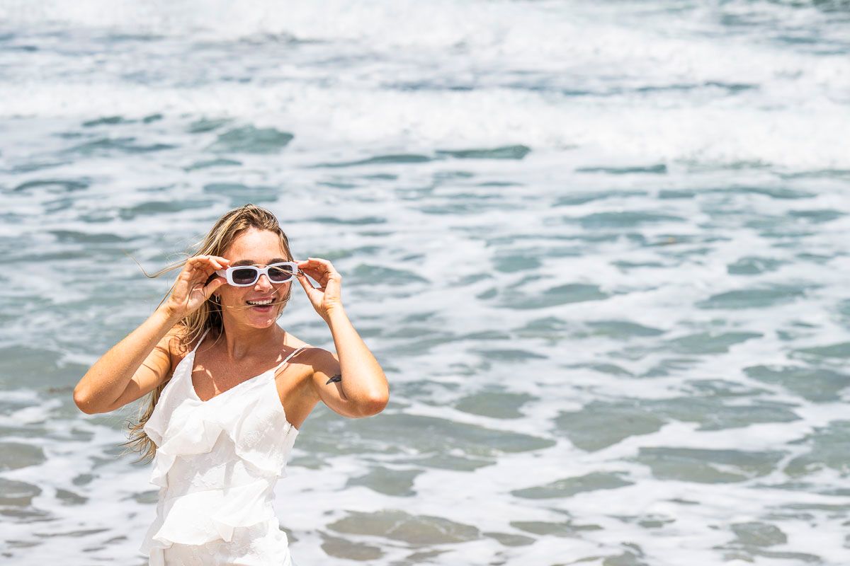 White dress and sunglasses against crashing ocean waves.