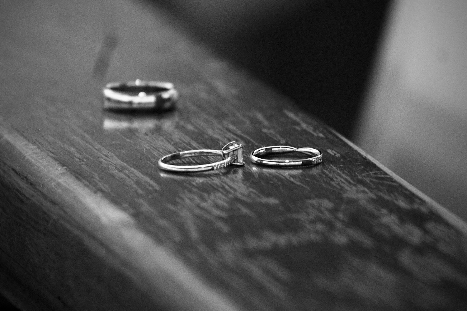 Black-and-white close-up of wedding rings on a wooden surface, representing the timeless moments we capture at Empax Studios.