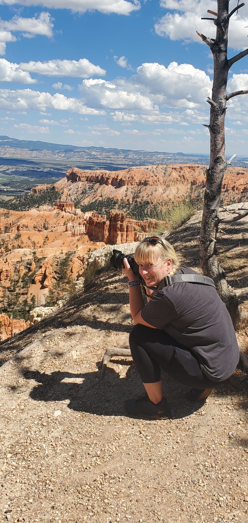 Visitor photographs the stunning orange rock formations and valleys of Bryce Canyon from a scenic overlook.