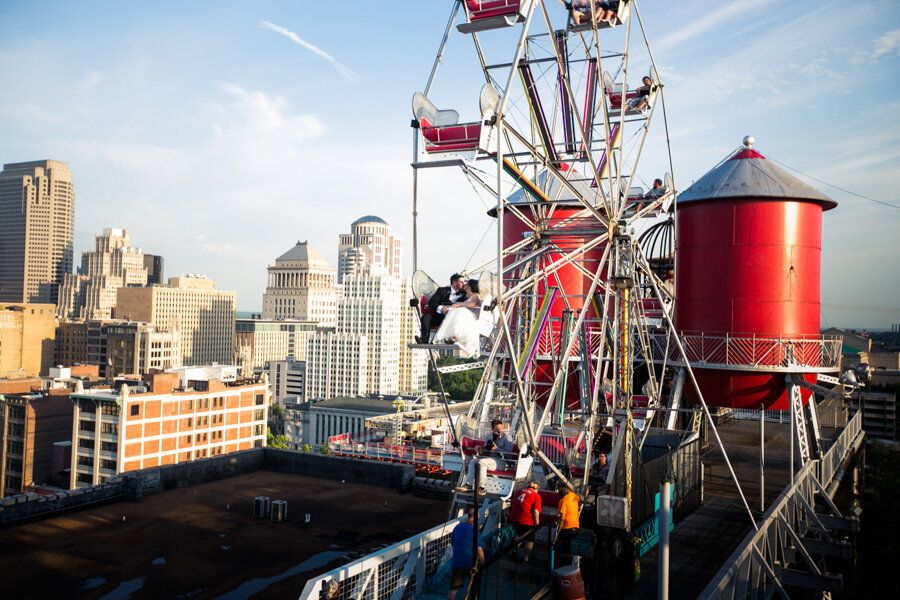 Red and white Ferris wheel against city skyline with water tower in view.