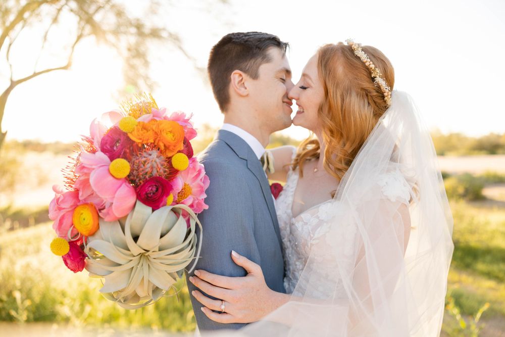 A romantic sunset portrait with the bride holding a vibrant bouquet of pink and orange flowers.